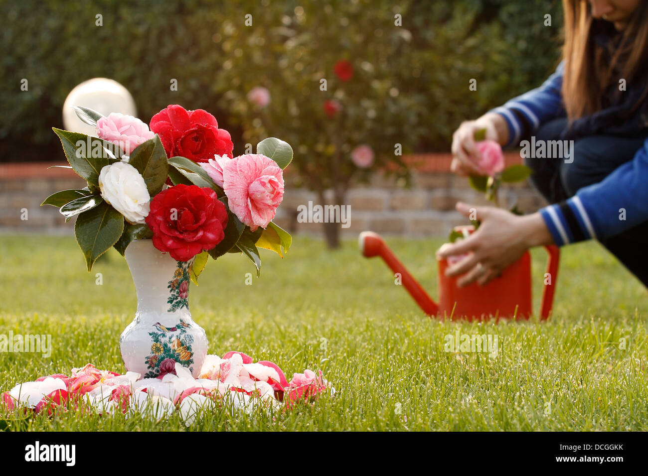 Una mujer prepara unas flores en el jardín de una fotografía. Foto de stock