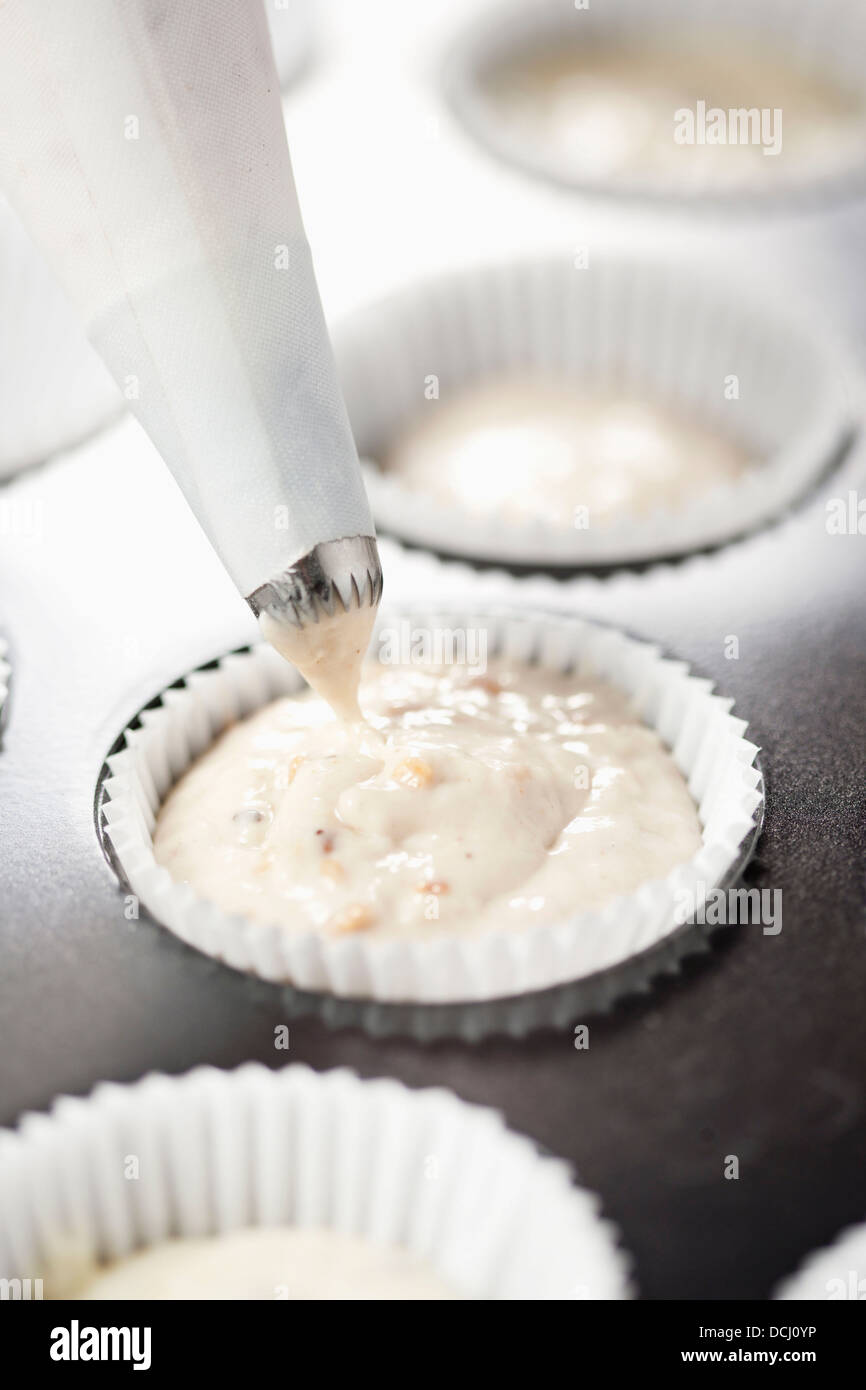 Rellenar los moldes de papel con la masa para hacer magdalenas Fotografía  de stock - Alamy