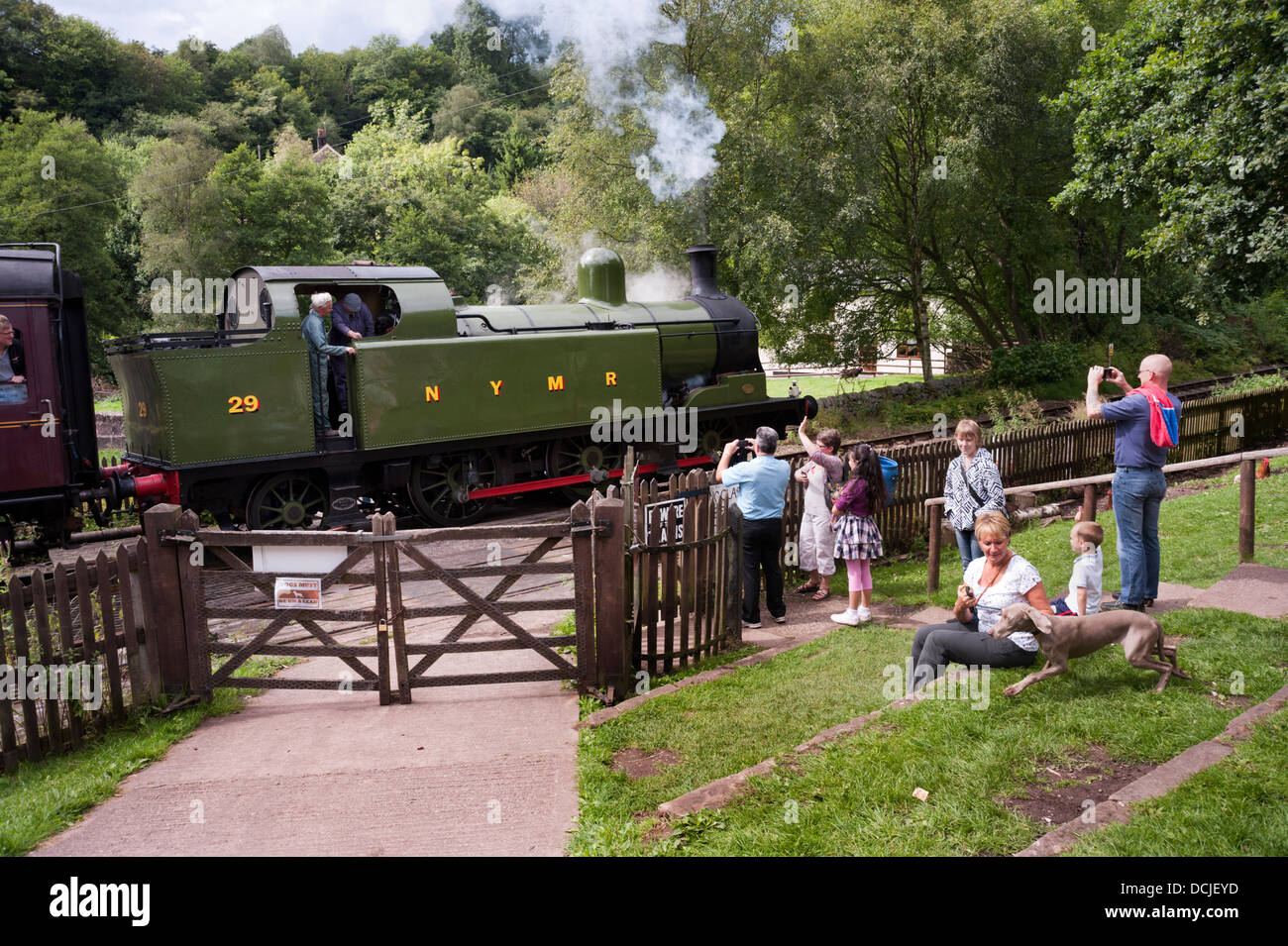 Los visitantes ola como un tren de vapor pasa el Black Lion PH en Consall Forge, en el Ferrocarril del Valle Churnet, puerro, Staffordshire, REINO UNIDO Foto de stock