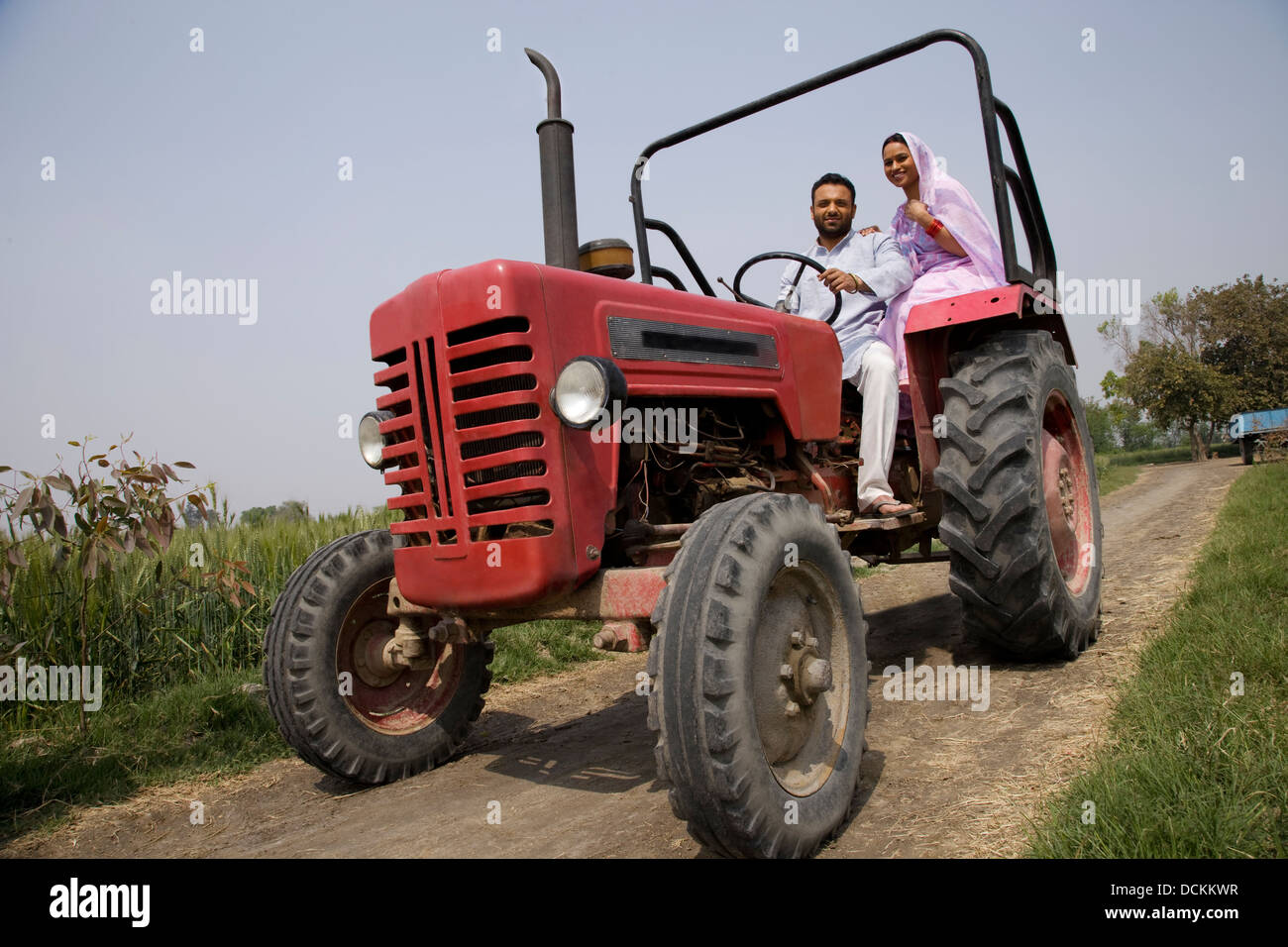 Ángulo de visión baja de un indio pareja sentada en un tractor Foto de stock