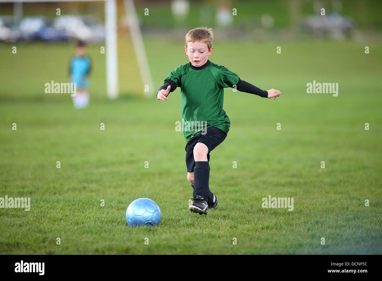 Joven pateando una pelota de fútbol Foto de stock
