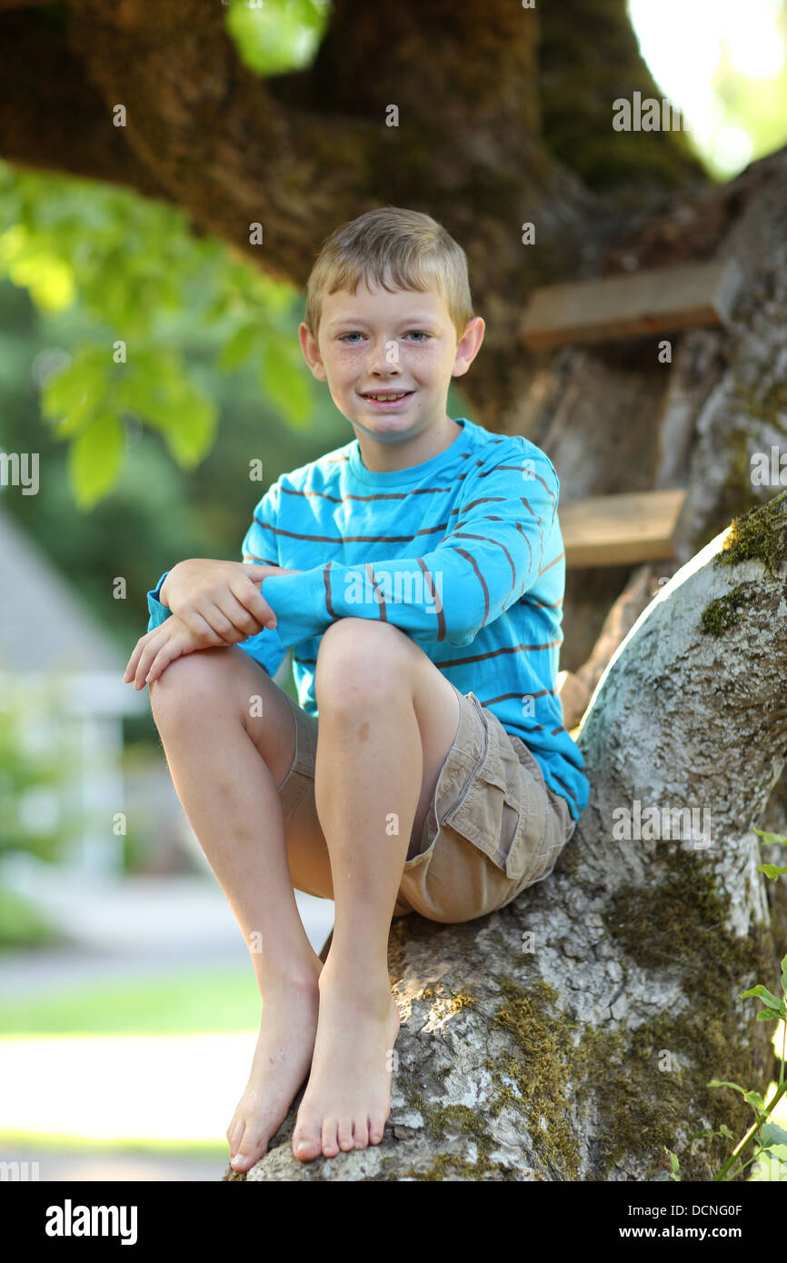 Retrato del joven muchacho sentado en el árbol Foto de stock