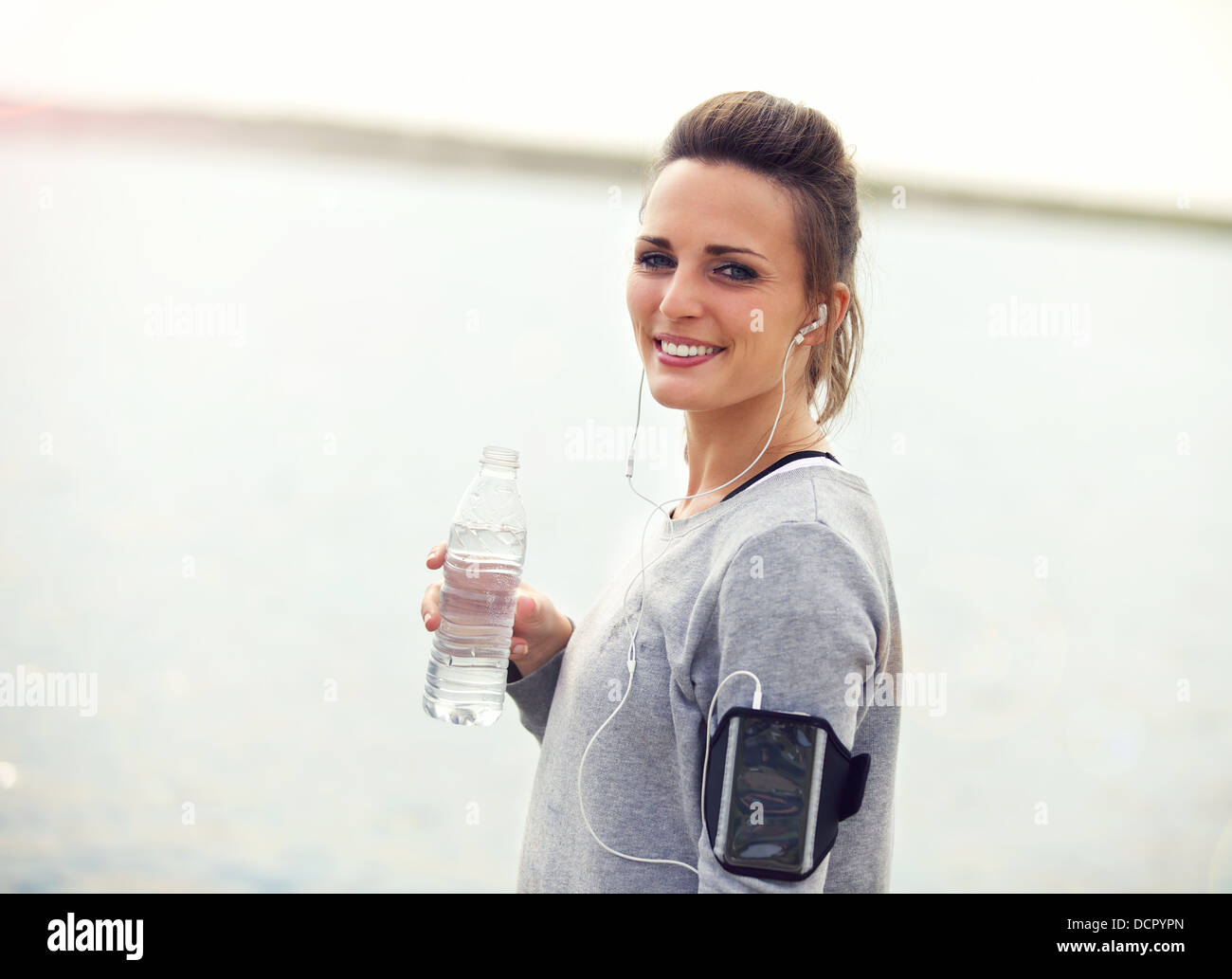 Mujer sonriente agua en un salto de agua embotellada holding Foto de stock