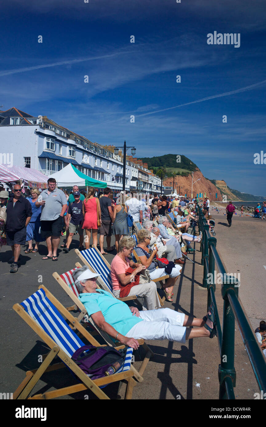 Relajarse en reposeras en la explanada durante el Festival Folclórico en Sidmouth Devon UK Foto de stock