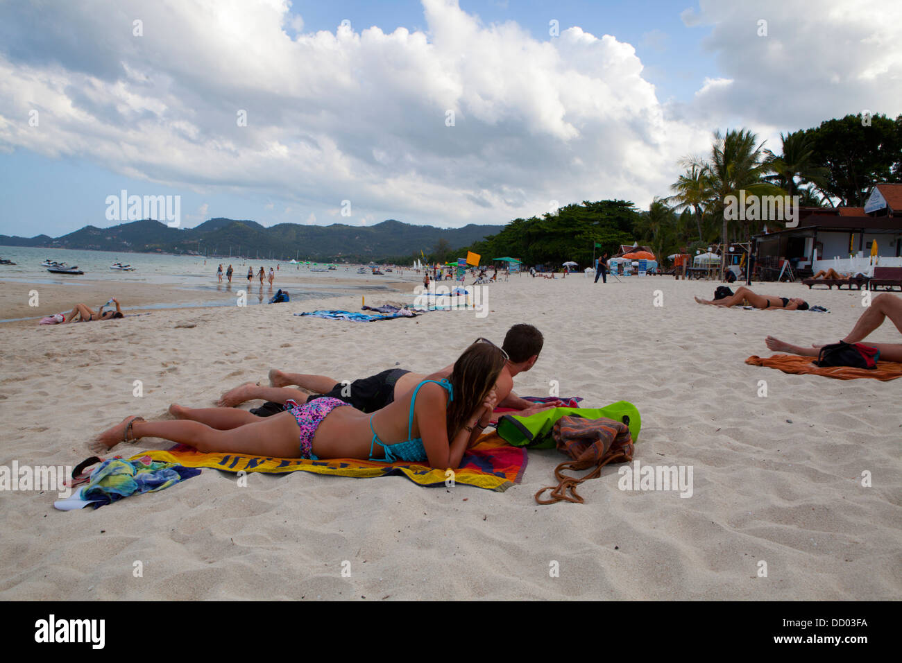 Un par sunbathes Hat Chaweng Beach en la isla de Ko Samui en el Golfo de Tailandia. Foto de stock