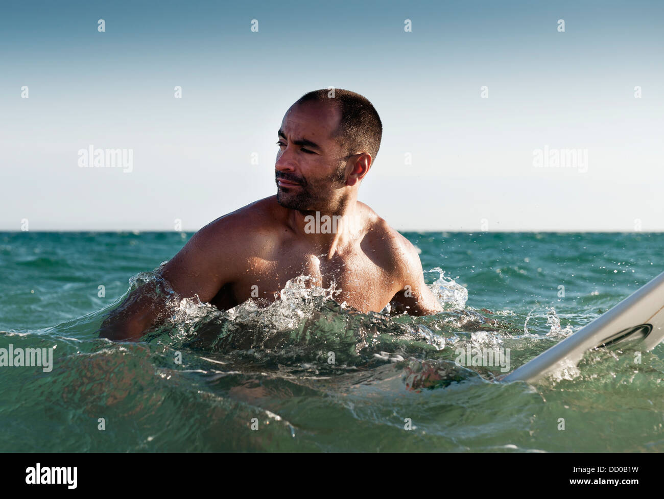 Un hombre con su tabla de surf en el agua; Tarifa, Cádiz, Andalucía, España Foto de stock