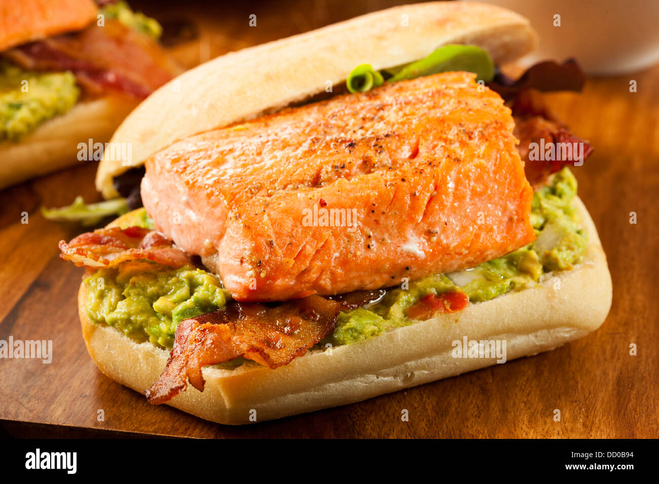 Sándwich de salmón a la parrilla con bacon y Guacamole sobre pan Foto de stock