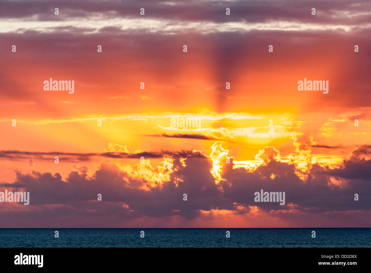 Toma dramática de los rayos de luz al atardecer sobre el océano. Foto de stock