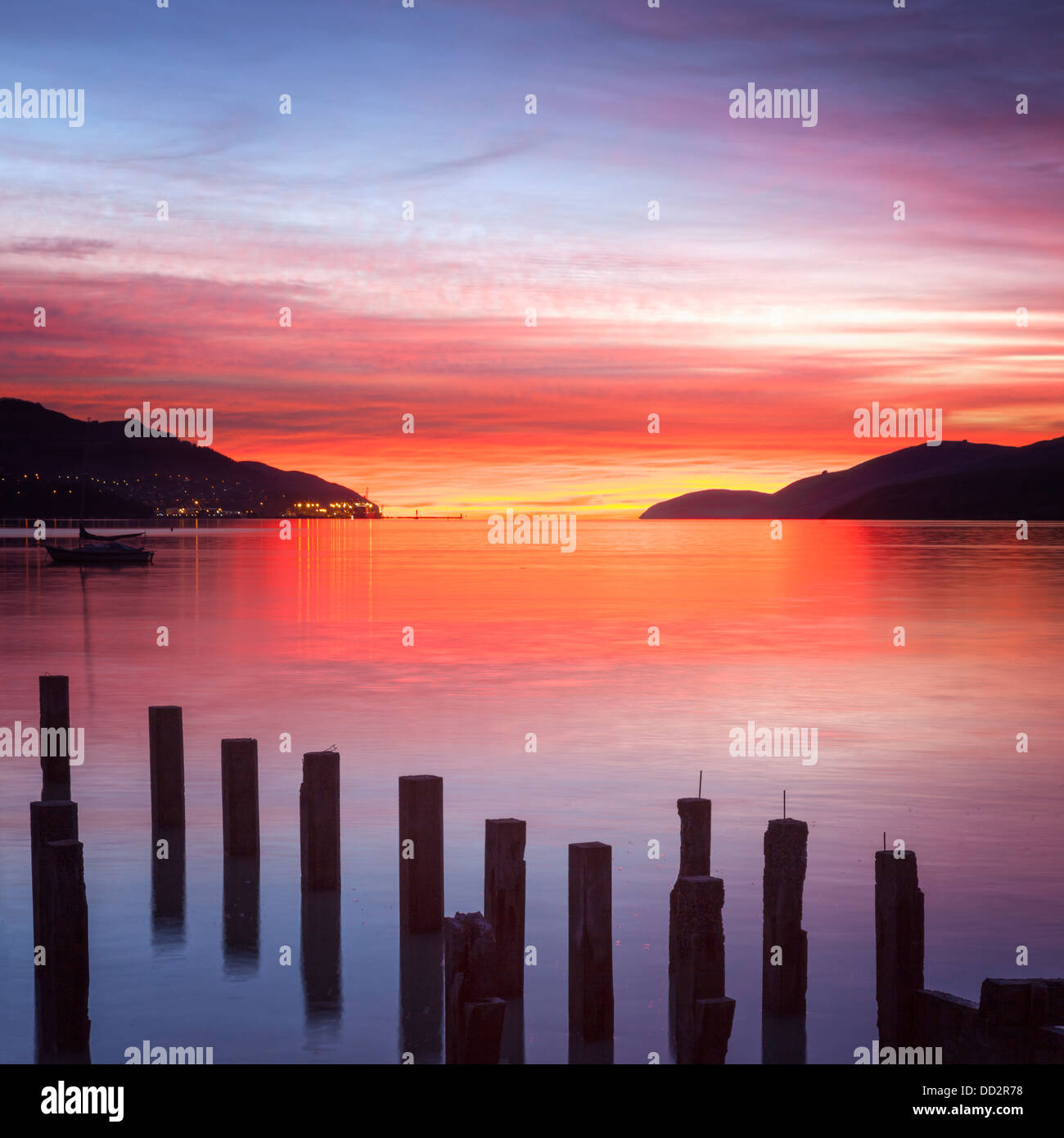 Hermoso amanecer con los colores rojo, naranja y púrpura, a través de Gobernadores Bay, Canterbury, Nueva Zelandia. En primer plano Foto de stock