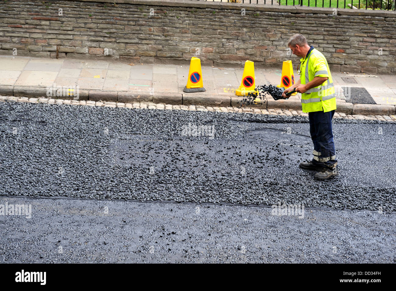 Workman extendiendo durante la repavimentación de carreteras de asfalto Foto de stock