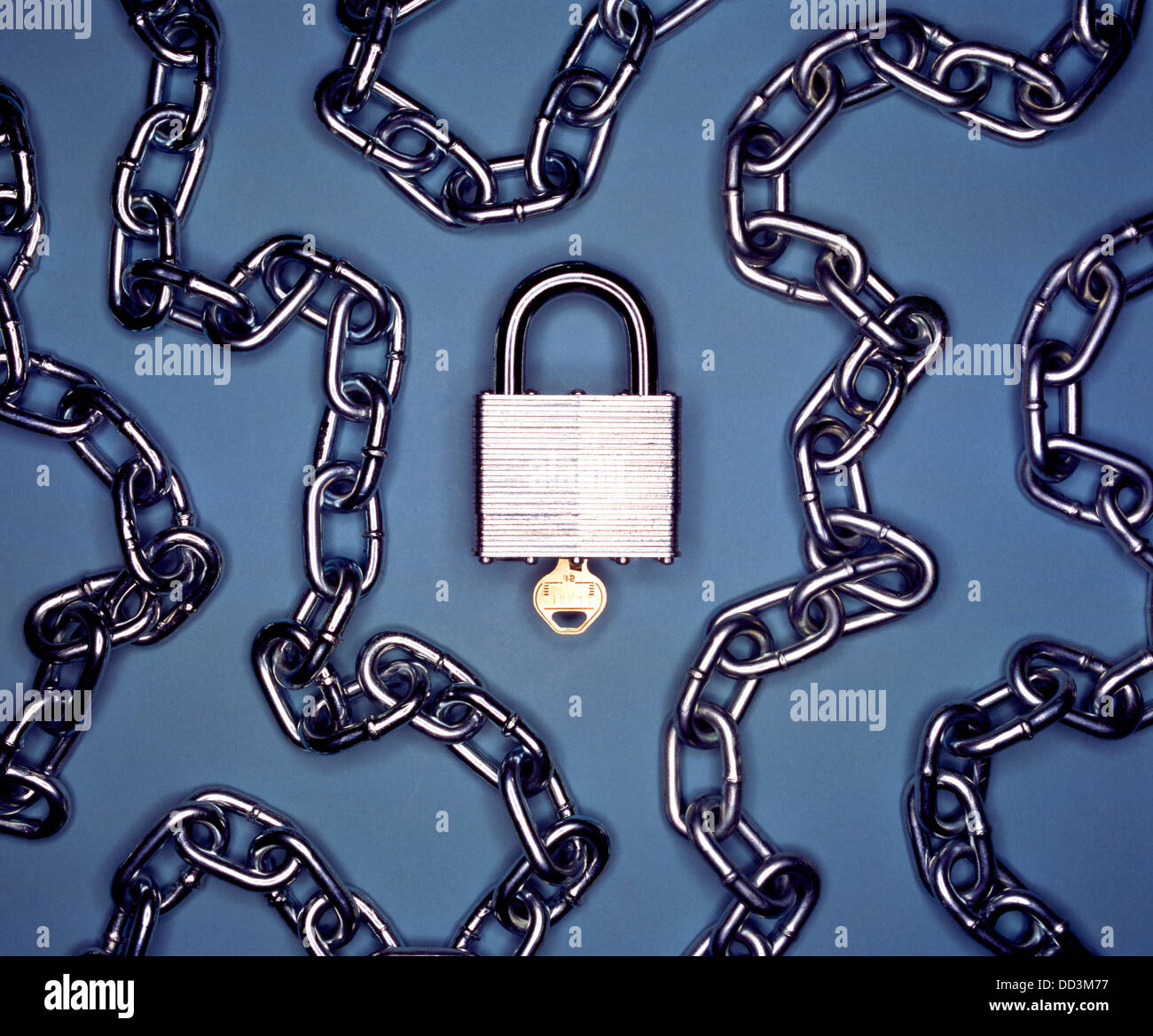 Un candado y llave de metal con cadena de metal sobre un fondo azul. Foto de stock