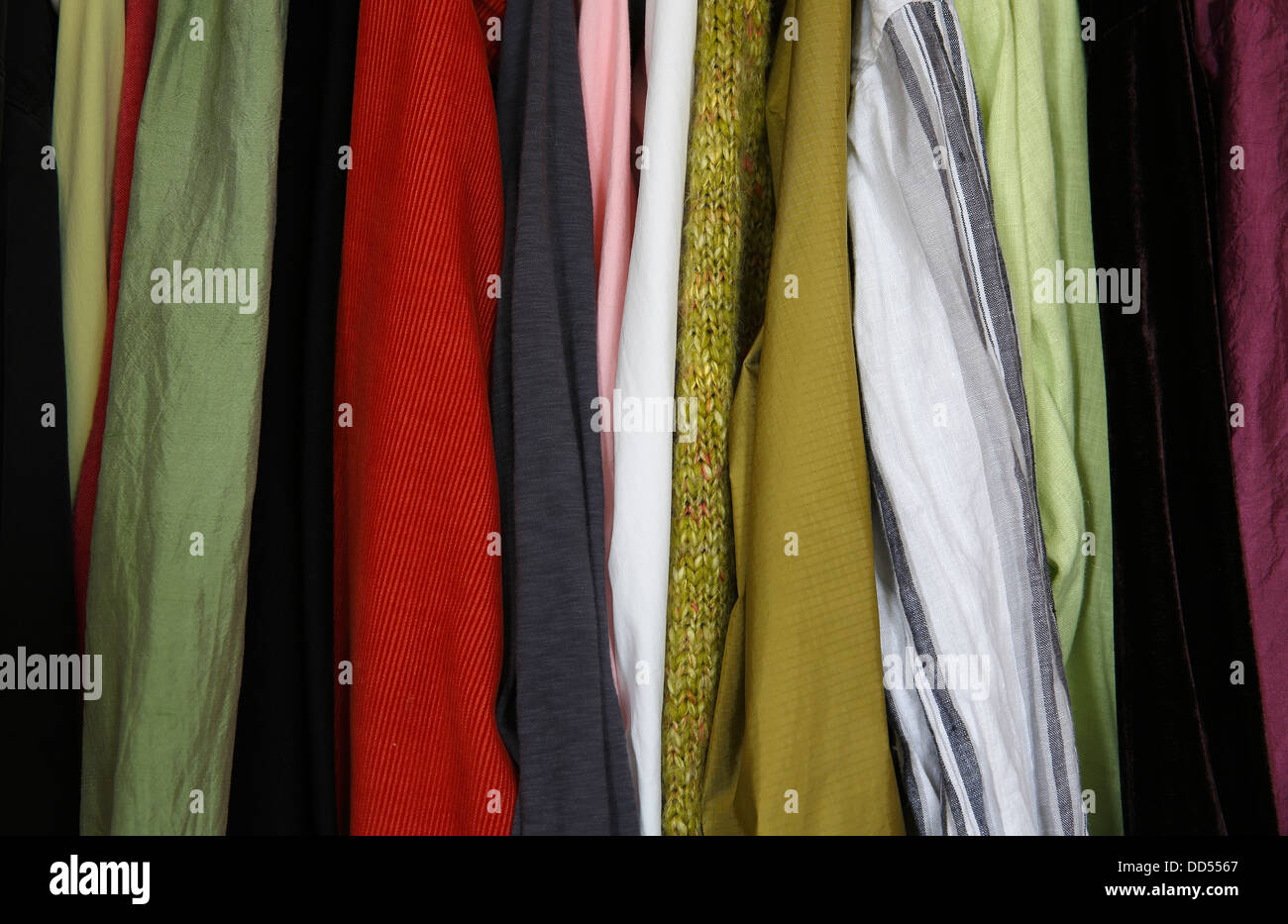 Telas de diferentes colores colgando de un closet Foto de stock
