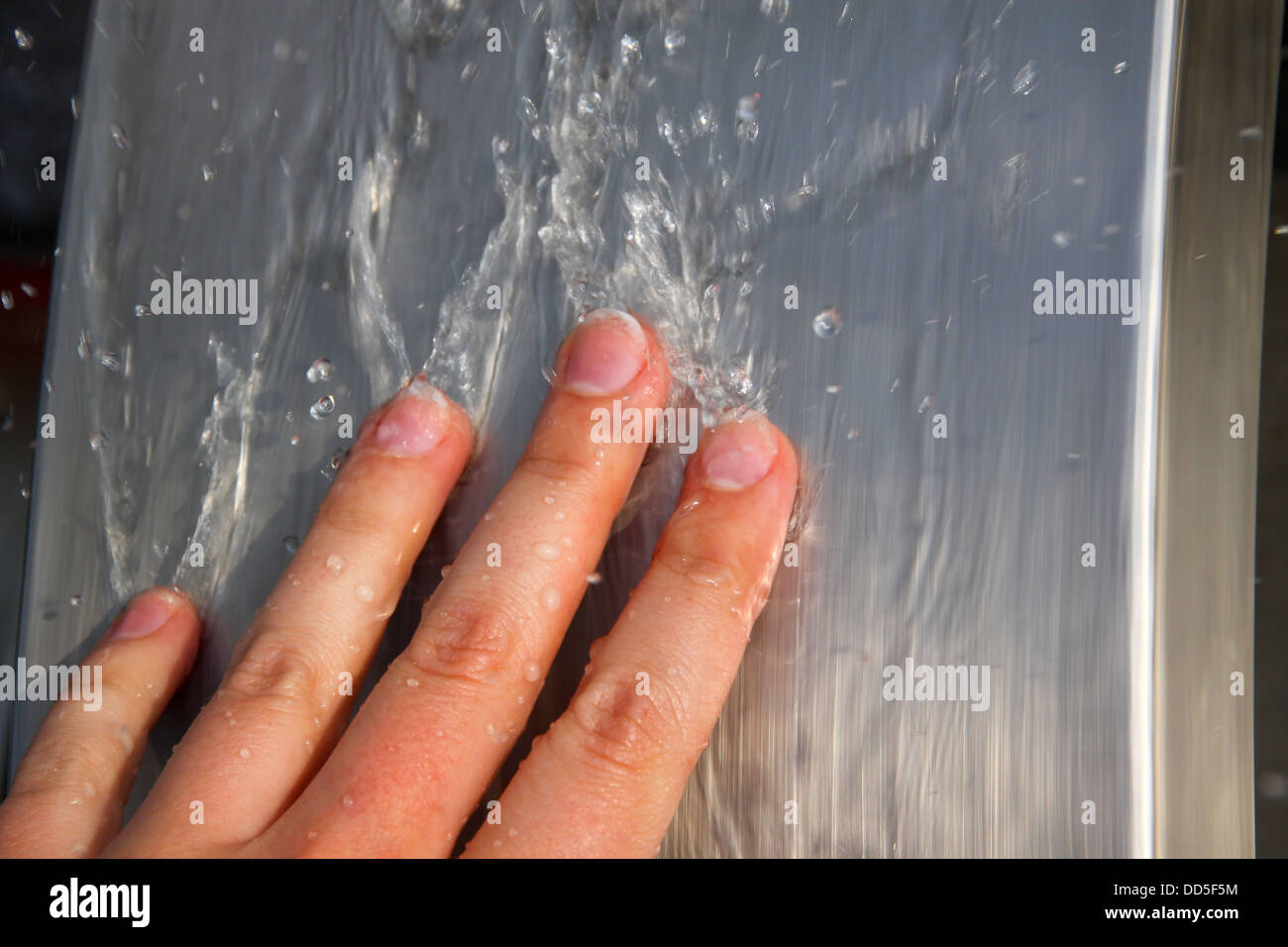 Los dedos del hombre en agua corriente. Foto de stock