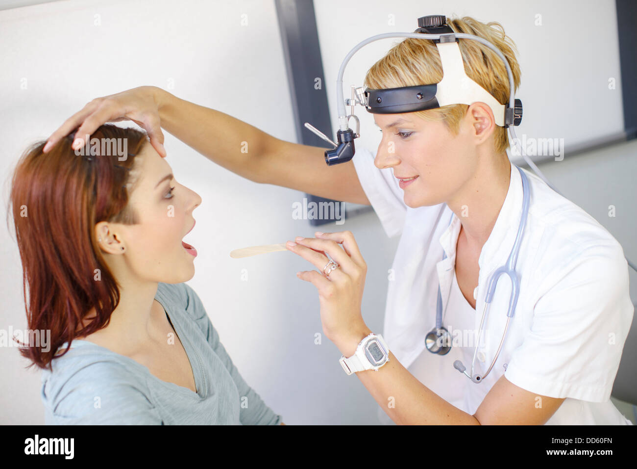 ENT médico examina la garganta de un paciente femenino Foto de stock