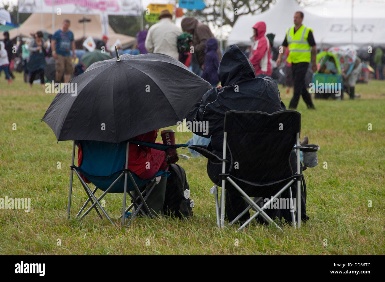 Vista horizontal de personas en un festival de música en la lluvia torrencial. Foto de stock