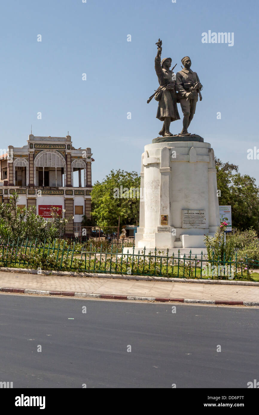 Dakar, Senegal. Place du Tirailleur, con estatua de Demba y Dupont, héroes de la I Guerra Mundial. La estación de tren de Dakar en el fondo. Foto de stock