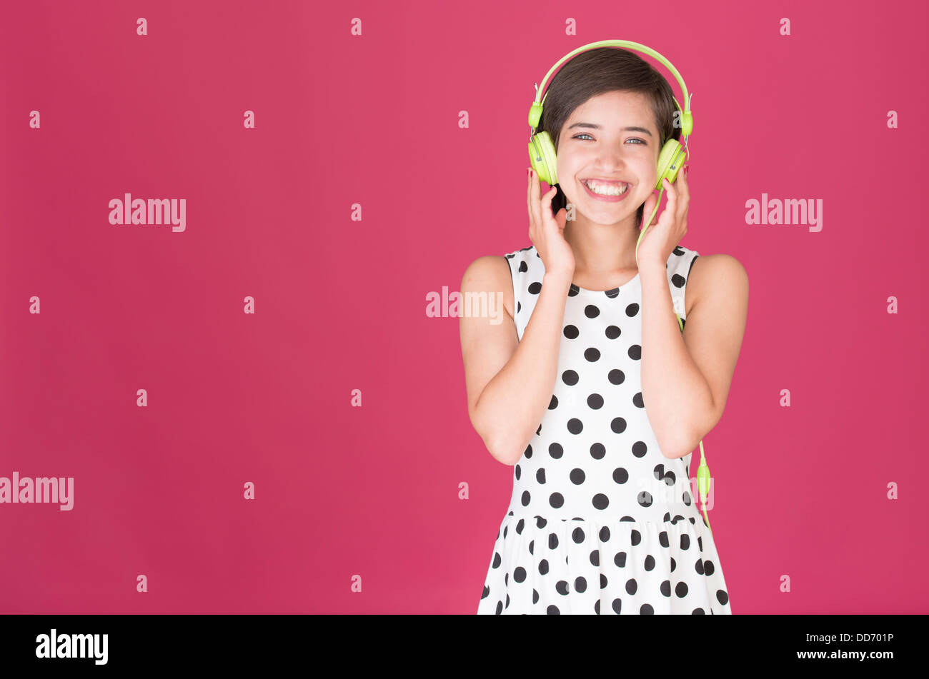 Joven y bella mujer multirraciales riendo y escuchar música con auriculares verde Foto de stock