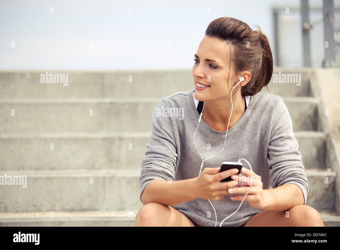 Feliz atleta atractivo sentarse y escuchar música mp3 mientras descansa Foto de stock