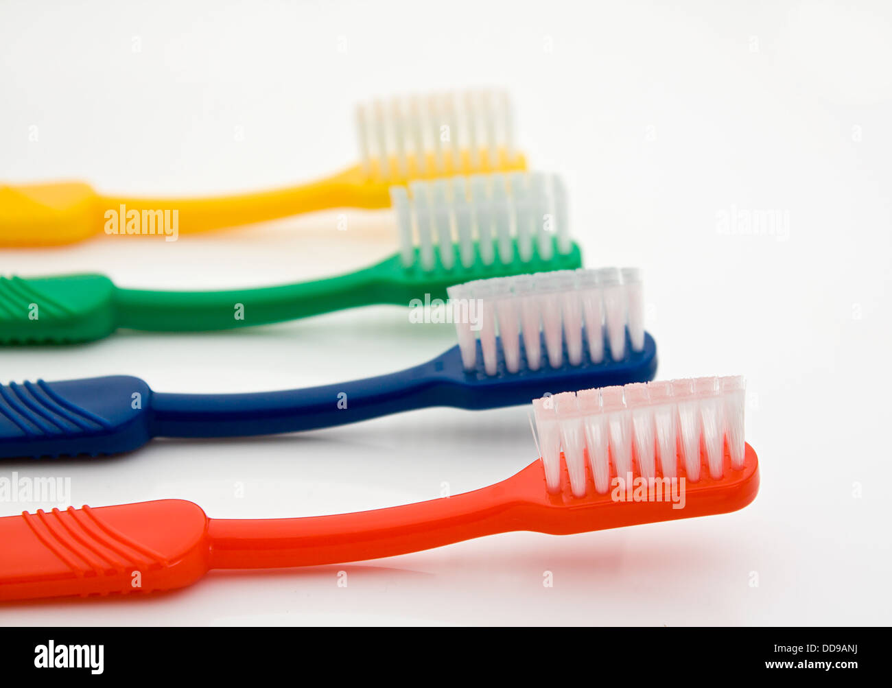 Detalle de una fila de cepillos de dientes de diferentes colores con el delantero en el enfoque selectivo buena para los dentistas Foto de stock