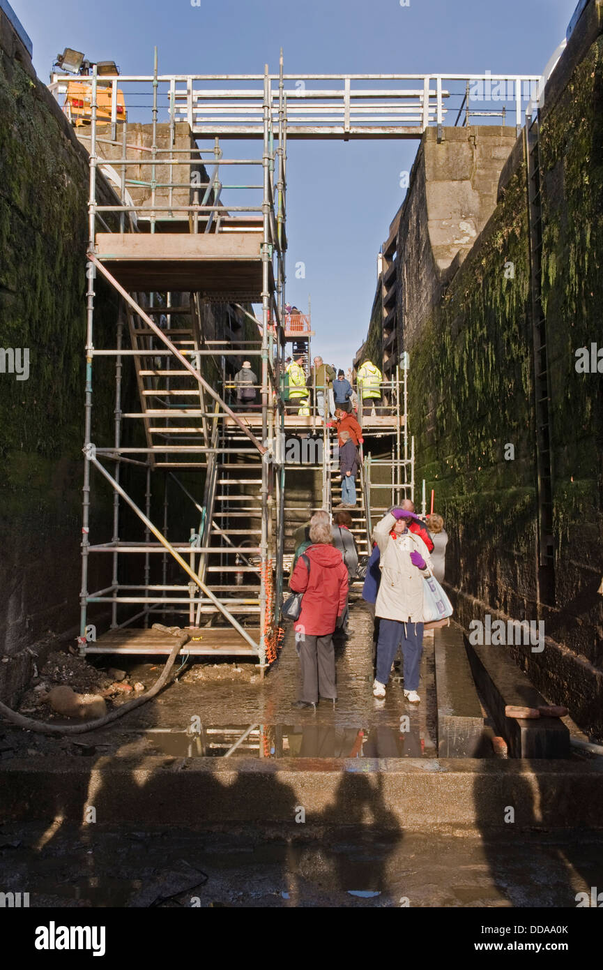 La gente dentro de una cámara de bloqueo drenado, recorriendo y mirando el trabajo de renovación - Jornada de puertas abiertas, Bingley cinco bloqueos de subida, West Yorkshire, Inglaterra, Reino Unido. Foto de stock