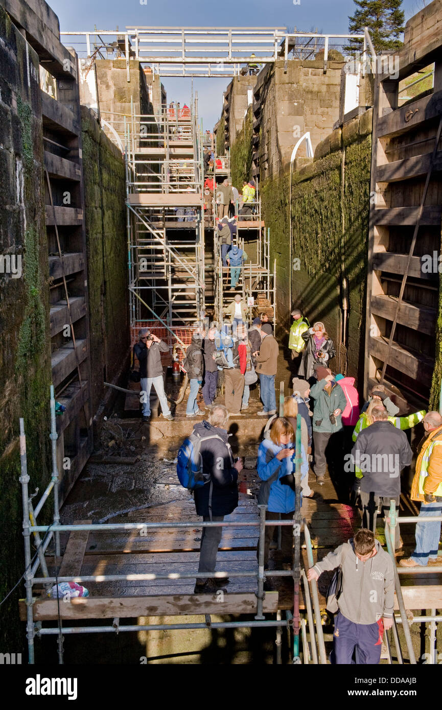 La gente dentro de una cámara de bloqueo drenado, recorriendo y mirando el trabajo de renovación - Jornada de puertas abiertas, Bingley cinco bloqueos de subida, West Yorkshire, Inglaterra, Reino Unido. Foto de stock