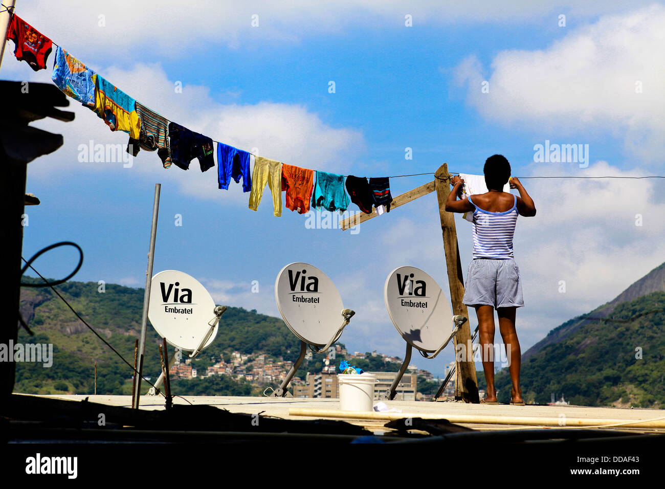 Mujer extendiendo la ropa en su casa losa de en la parte superior de la Favela Santa Marta de Río de Janeiro, Brasil TV satélite Dish Fotografía de stock - Alamy