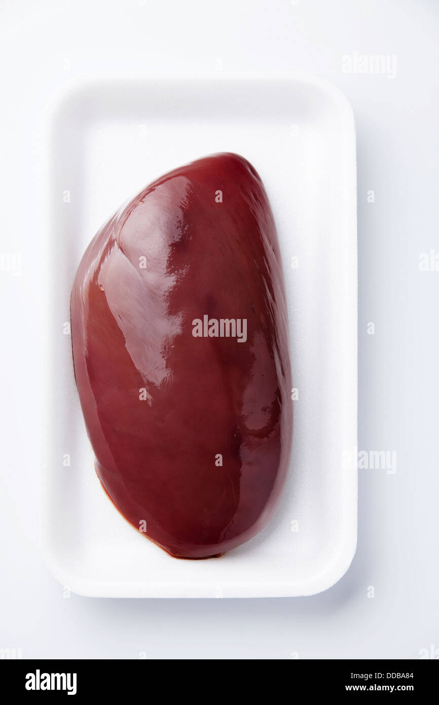 Hígado crudo en caja de plástico sobre fondo blanco. Foto de stock