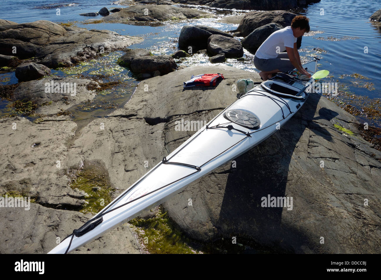 Una mujer packs su kayak para un tour Foto de stock