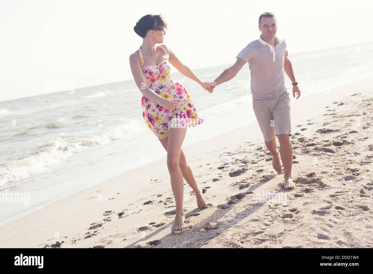Imagen dinámica de marcha pareja en la playa. Cogidos de la mano. Verano divertido Foto de stock