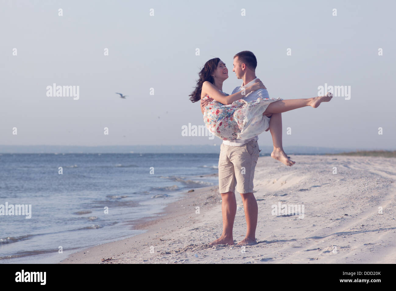 Feliz pareja joven en ropa blanca tienen recreación romántica y diversión en la hermosa playa de vacaciones Foto de stock