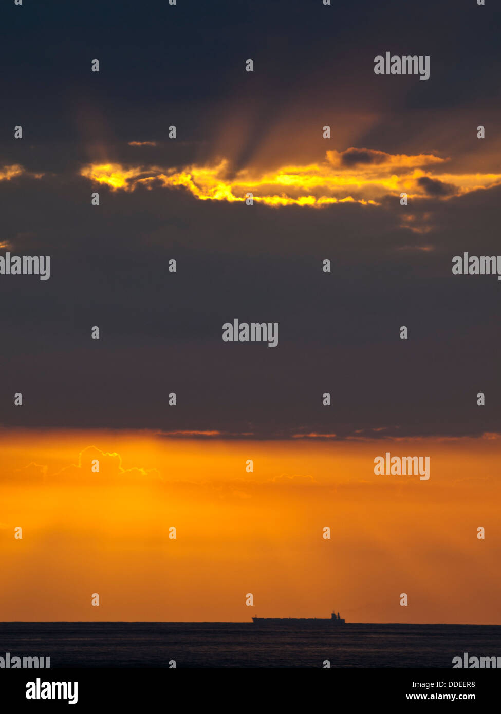 Carguero silueta en la línea del horizonte con luz naranja atardecer Foto de stock