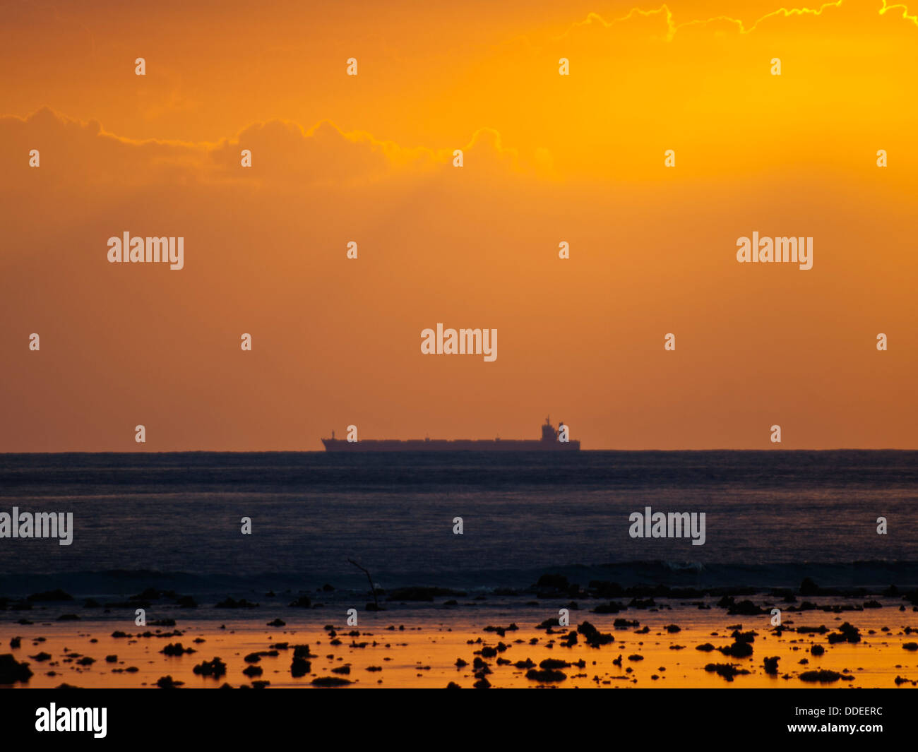 Carguero silueta en la línea del horizonte con luz naranja atardecer Foto de stock