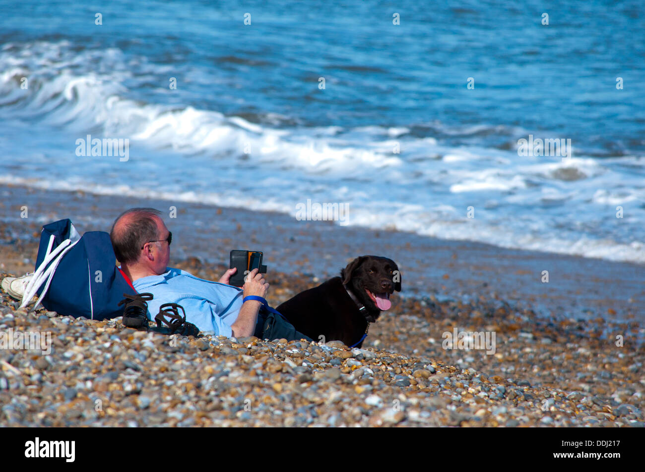 Hombre leyendo kindle e reader en la playa Foto de stock