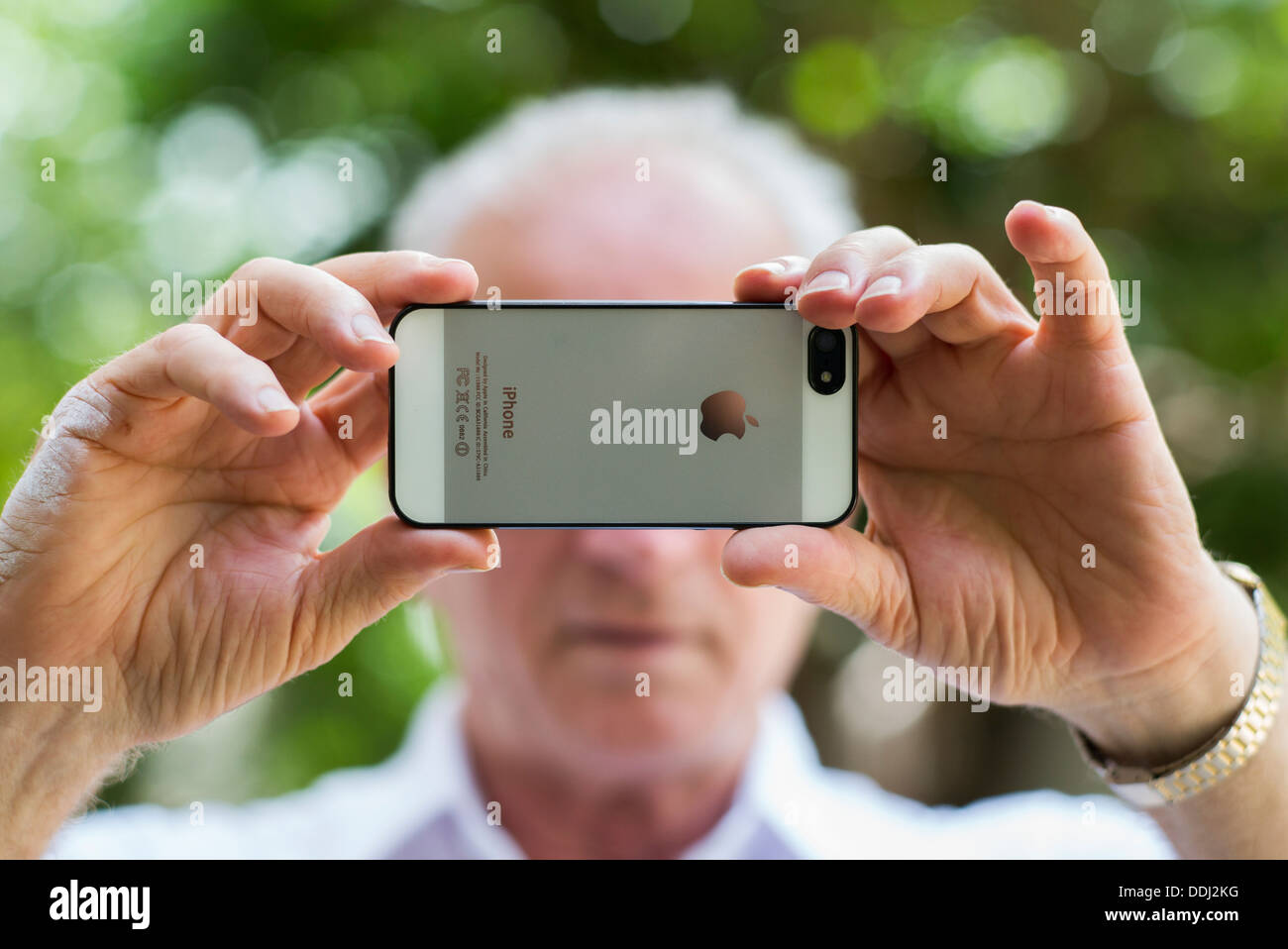 Hombre Senior tomando una fotografía con un iphone de Apple Foto de stock