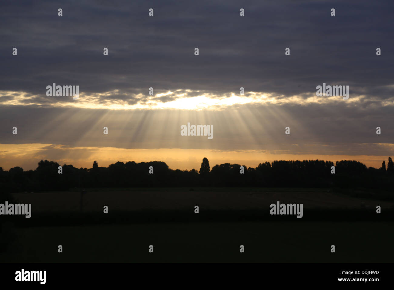 Los rayos de luz a través de una lenta pesada capa de nubes para iluminar una zona desconocida de la campiña inglesa de una mañana temprana Foto de stock