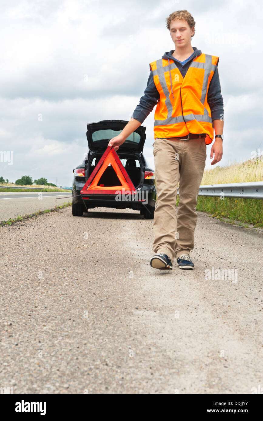 Hombre caminando lejos de su coche roto con un de advertencia y chaleco de seguridad de seguridad vial Fotografía de - Alamy