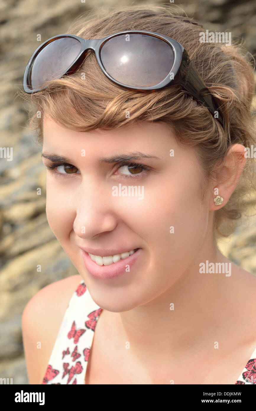 Atractiva mujer joven con cabello castaño y ojos marrones, gafas de sol y sombra Foto de stock