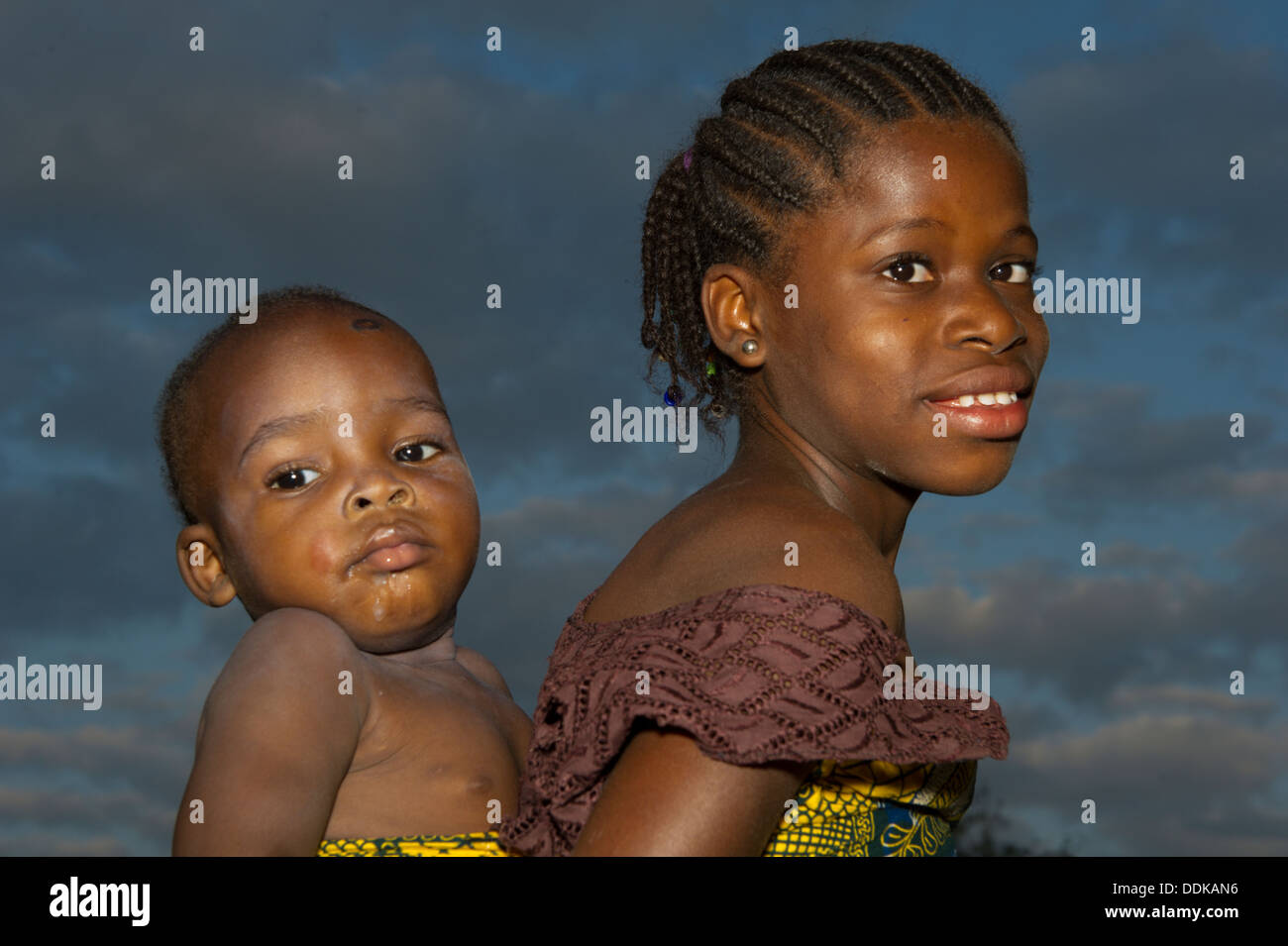 Un adolescente atrás llevando un niño en Nigeria Foto de stock