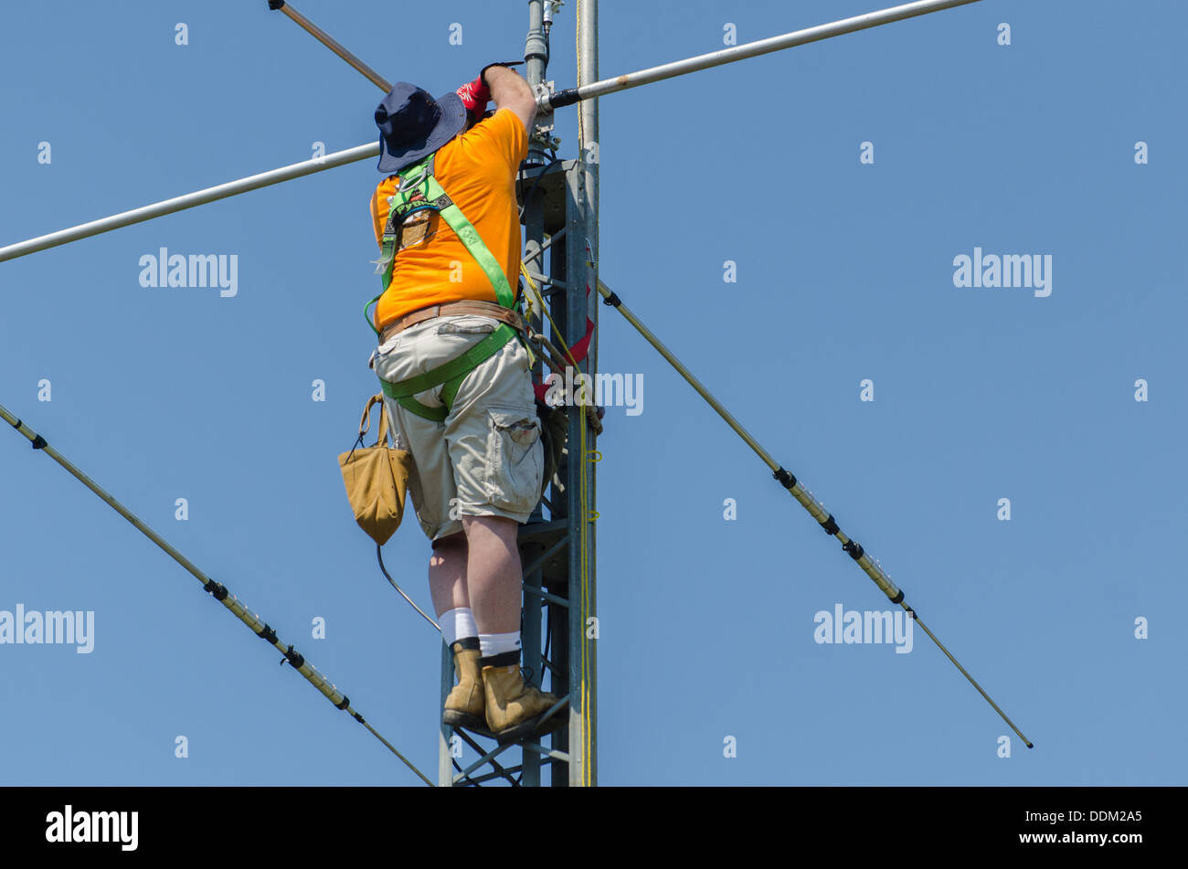 El hombre instalar una antena de radio amateur en la parte superior de la torre de la radio. Foto de stock