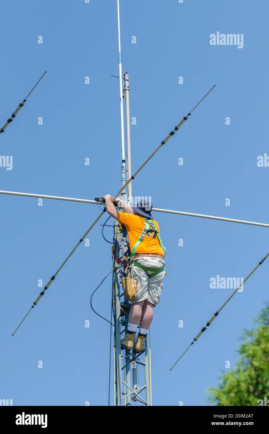 El hombre instalar una antena de radio amateur en la parte superior de la torre de la radio. Foto de stock