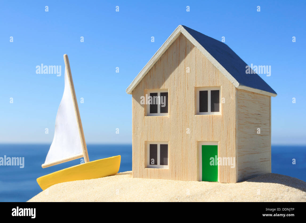 Casa modelo y barco por el océano Foto de stock
