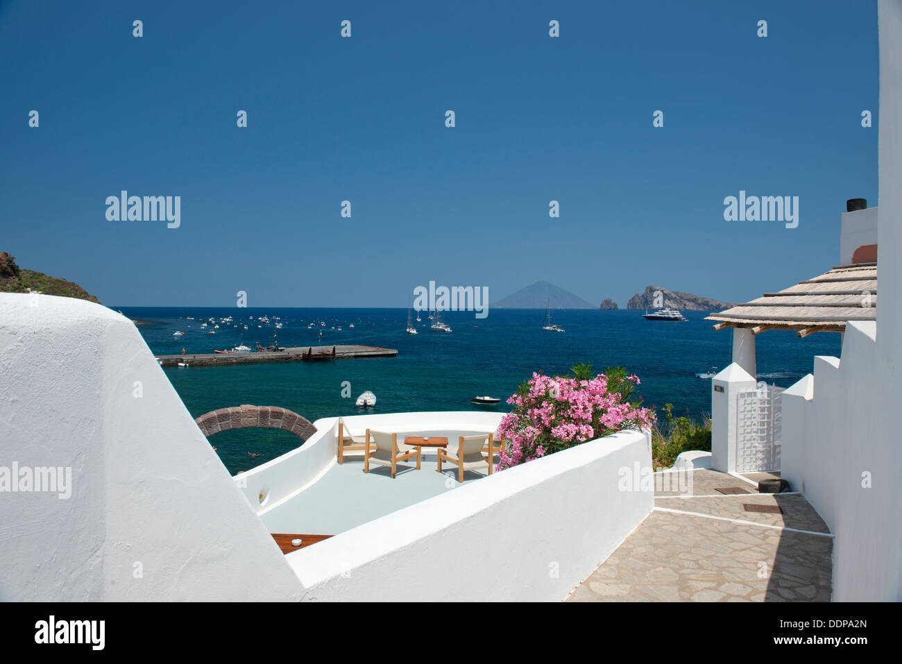 Las paredes encaladas y adelfa que rodea una terraza mirando al Stromboli en Panarea, las Islas Eolias, en Sicilia, Italia Foto de stock