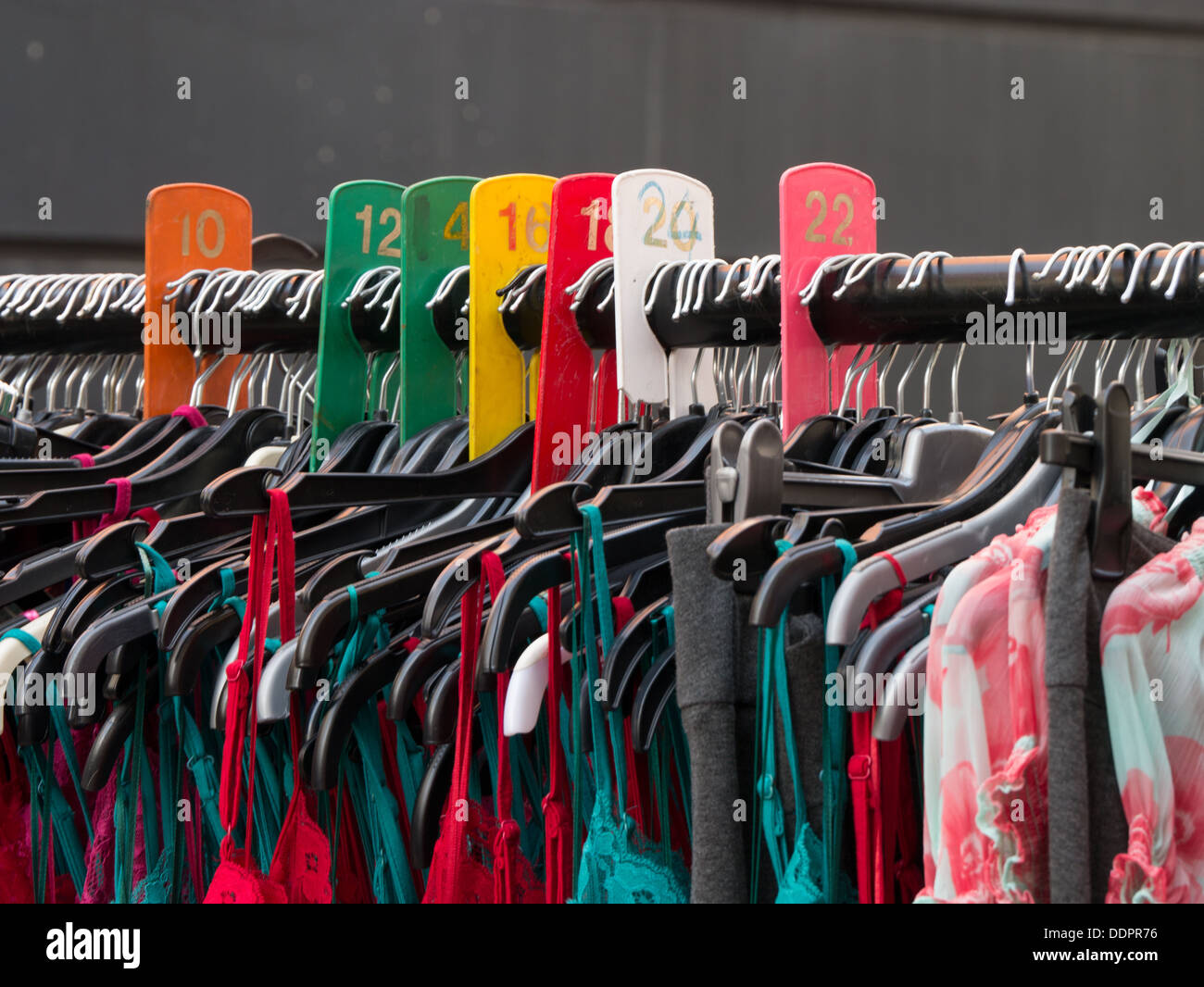 Coloridos vestidos colgando en Petticoat Lane market street en Londres Foto de stock