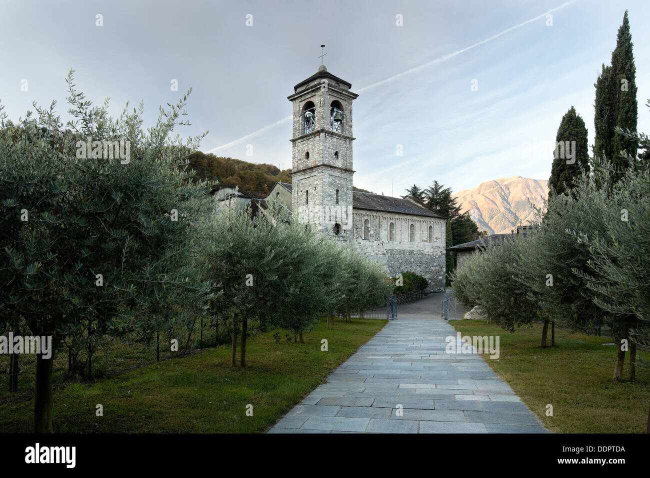 Vista exterior del ábside, la torre campanario y el lateral de la Abadía de Piona, Lago de Como, Italia del norte de camposanto y jardines con pathwa Foto de stock