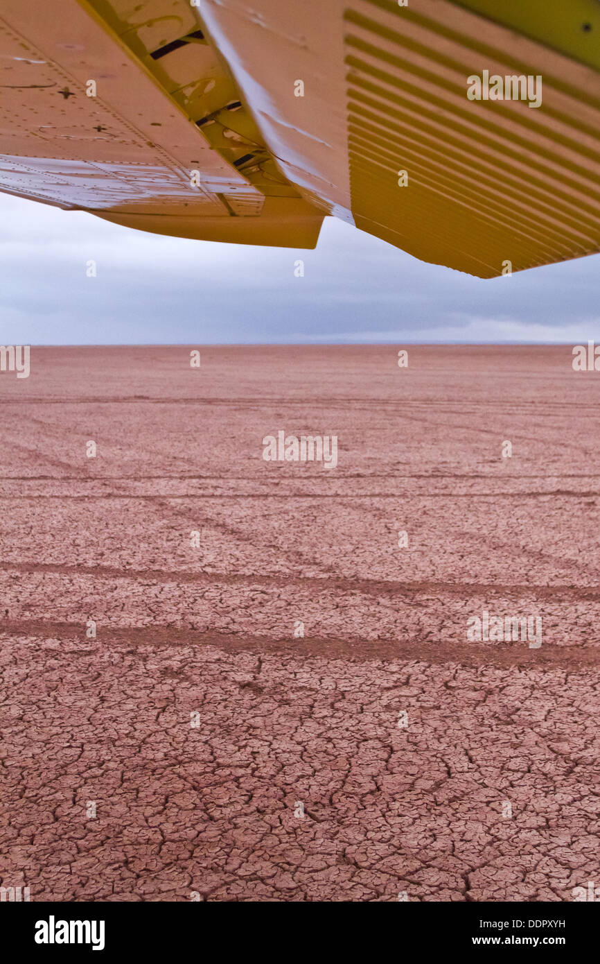 Vista bajo el ala del avión Cessna amarillo abierto sobre el lecho del lago seco , Amboseli, Kenia, África Oriental Foto de stock
