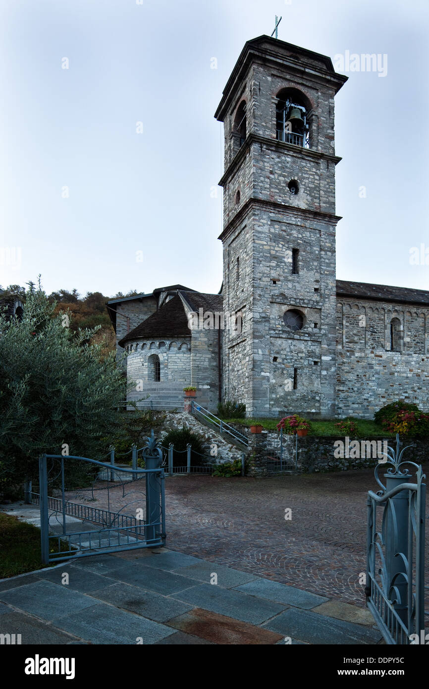 Vista exterior del ábside, la torre campanario y el lateral de la Abadía de Piona, Lago de Como, Italia del norte de camposanto y jardines a principios de mor Foto de stock