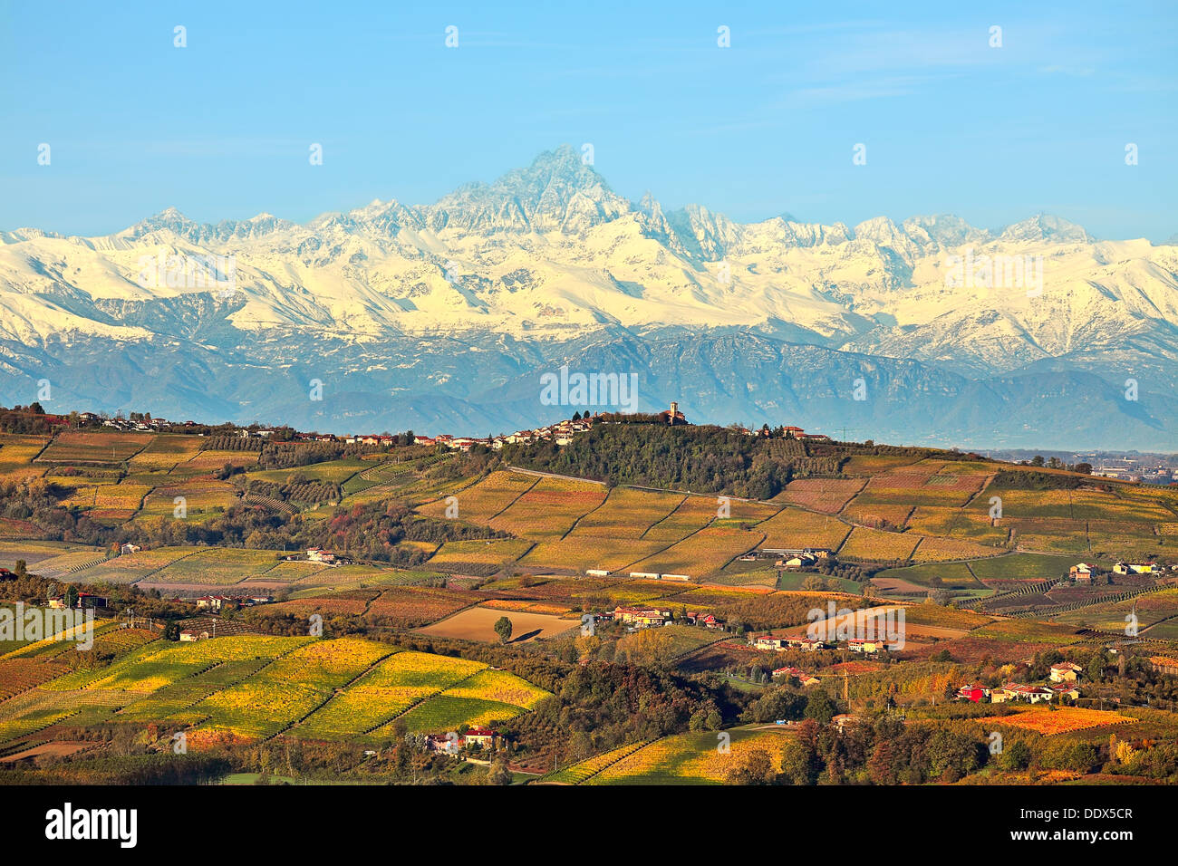 Vista otoñal de colinas con viñedos y picos montañosos nevados de fondo en el Piamonte, Norte de Italia. Foto de stock
