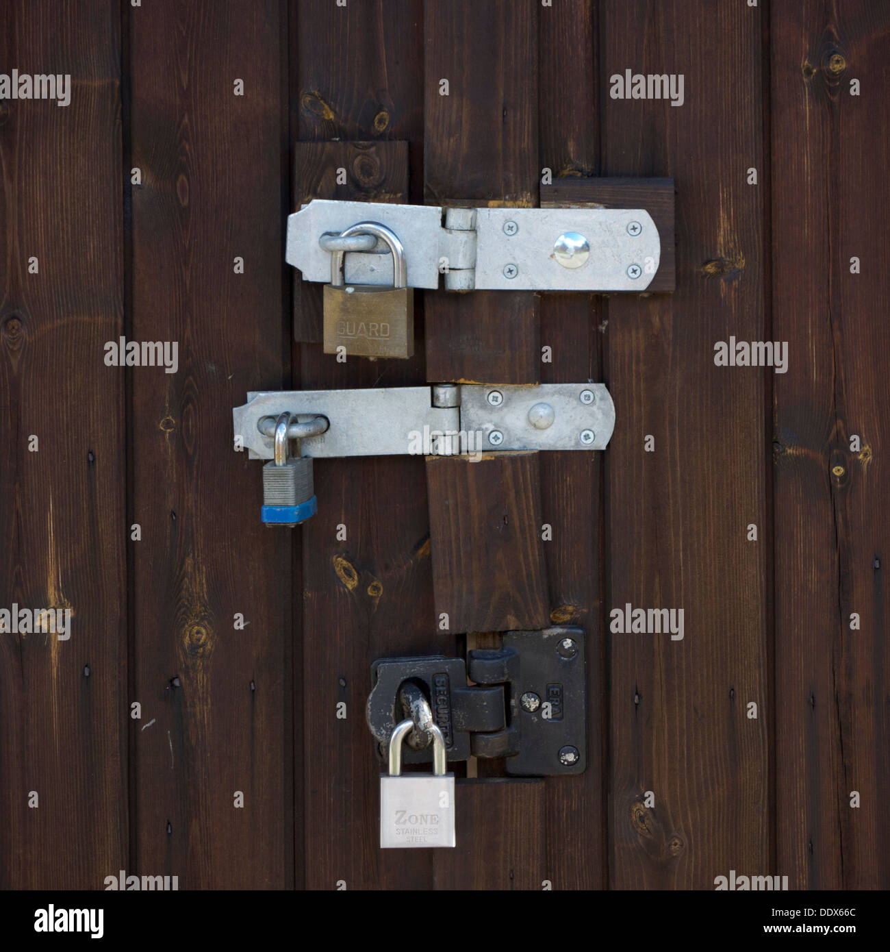 Una foto de tres fuertes candados bloqueo de una puerta de garaje de madera  para la seguridad Fotografía de stock - Alamy