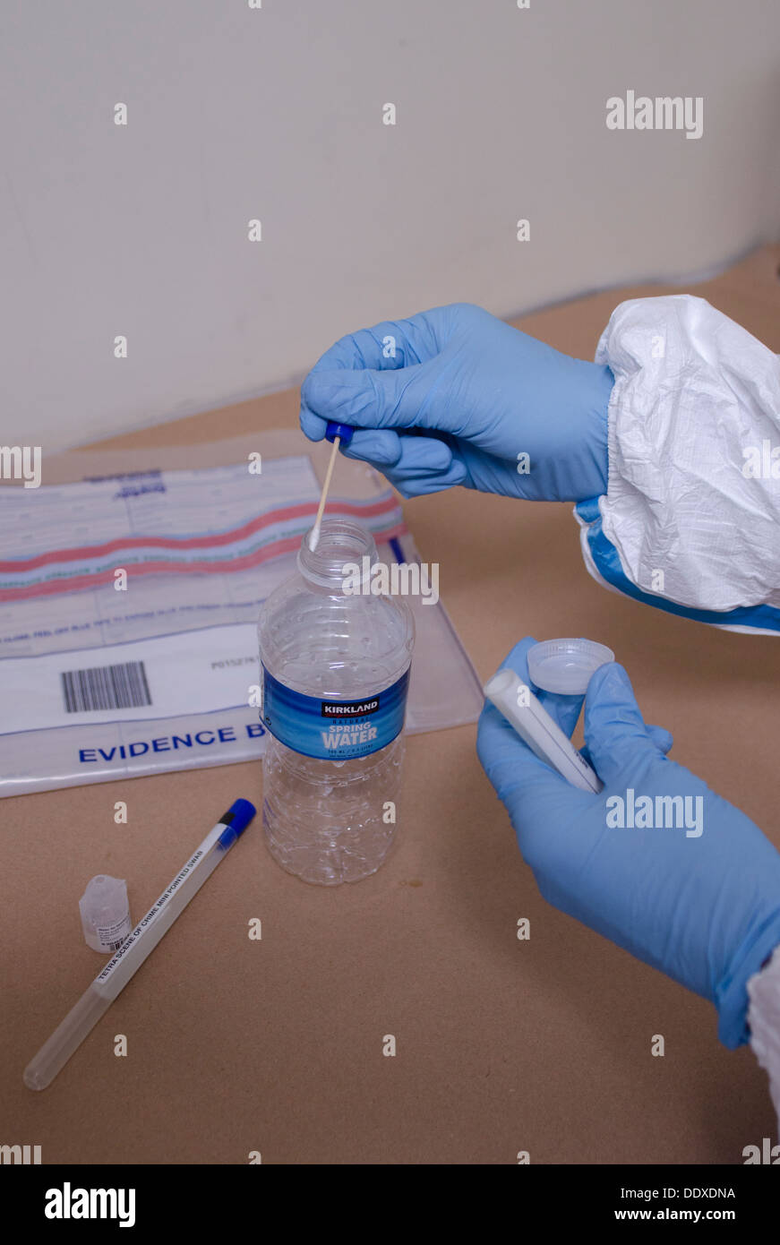 Un investigador de la escena del crimen (CSI) se frotará la llanta de una botella de agua para fines de ADN Foto de stock