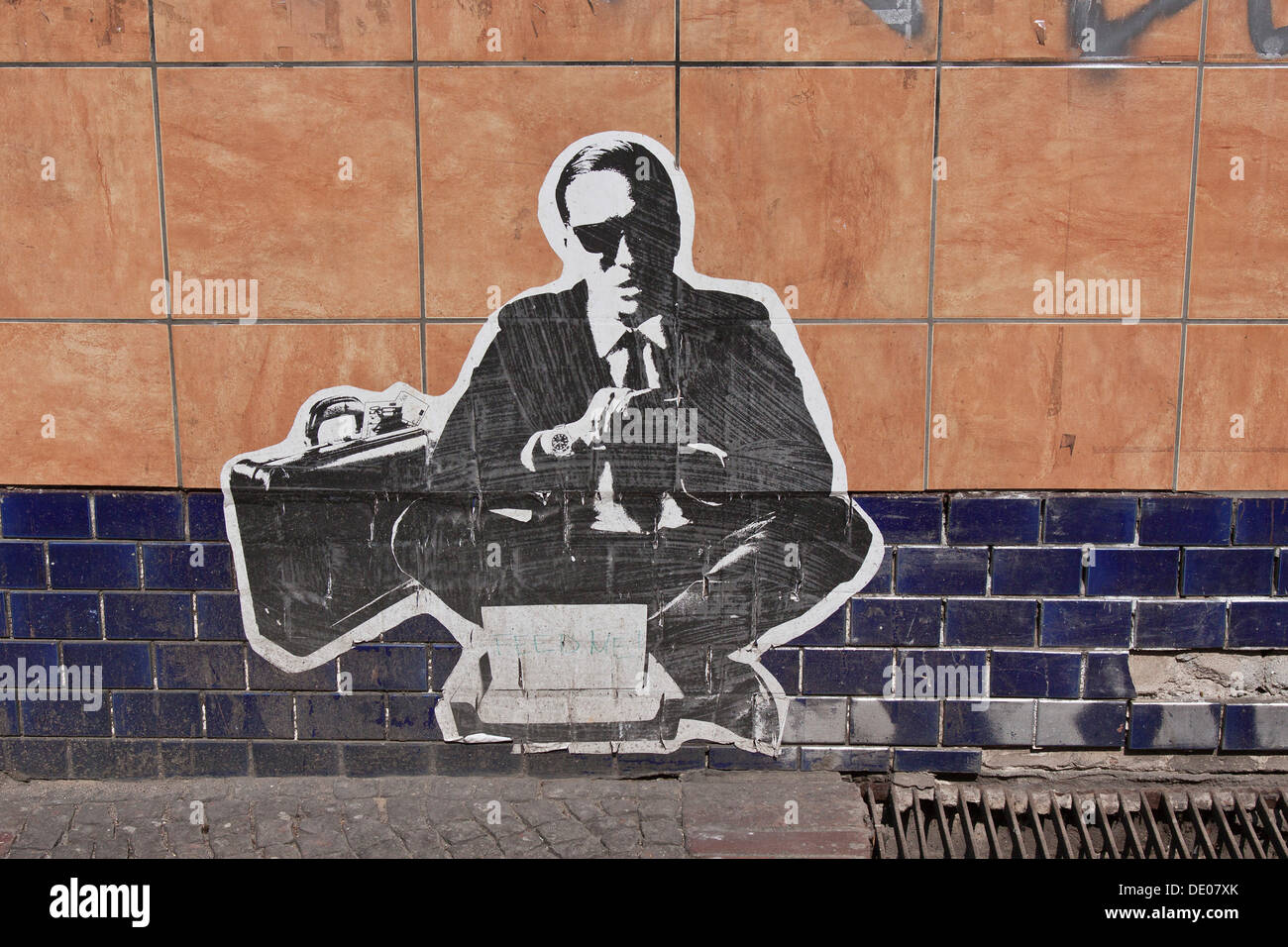 Hombre vestido con un traje, banquero o empresario con un maletín, un cartel pegado en una pared, Berlín Foto de stock